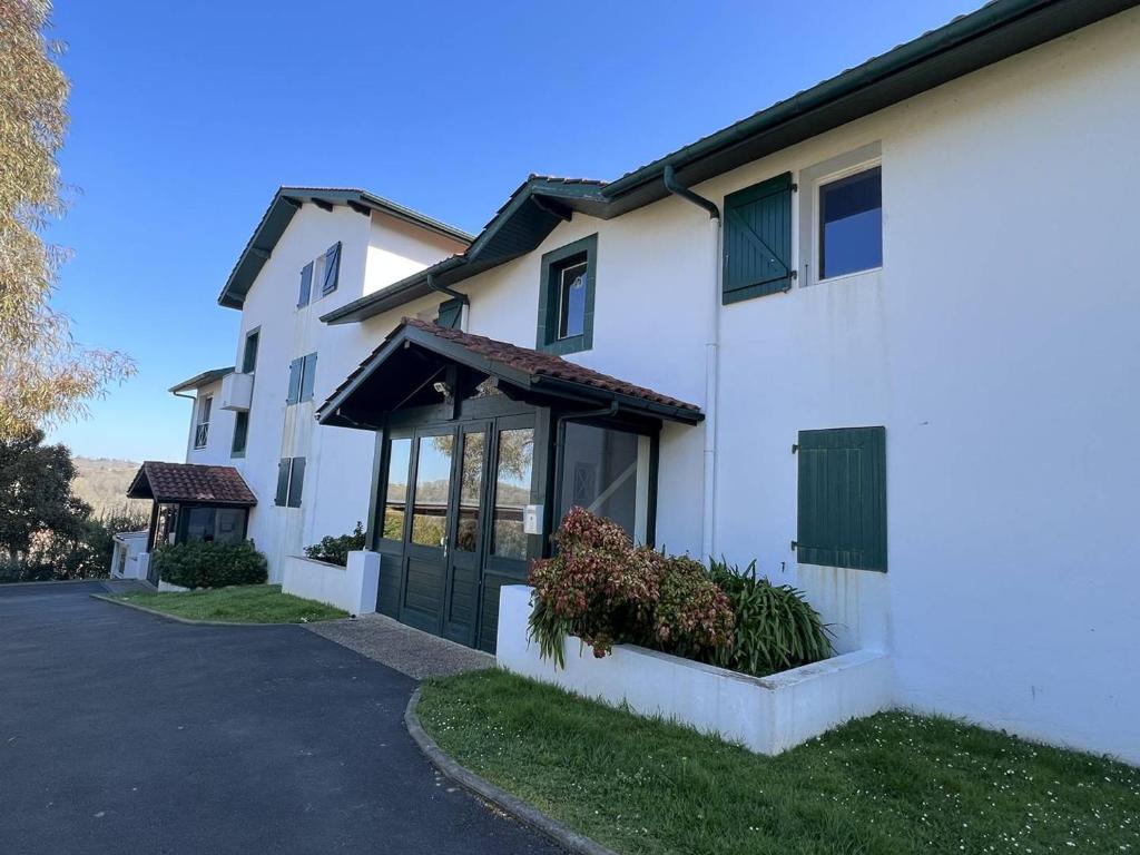 a white house with a green door on a street at Appartement T2 confortable avec terrasse sud et parking, au calme, proche commerces, petit animal accepté - FR-1-495-6 in Cambo-les-Bains
