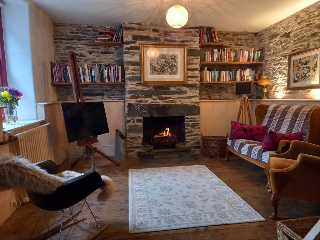 a living room with a fireplace and a couch and a tv at Chapel Cottage in Machynlleth