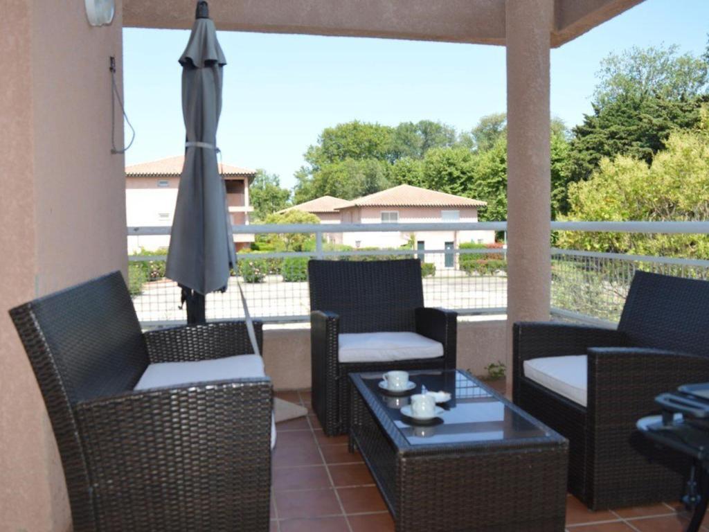 une terrasse avec des chaises, un parasol et une table dans l'établissement Appartement 3 Pièces à Saint-Cyprien : 6 Couchages, Piscine, Terrasse, Parking et WIFI - FR-1-225D-68, à Saint Cyprien Plage