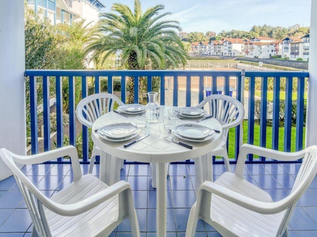 une table blanche avec quatre chaises sur un balcon dans l'établissement Appartement avec Terrasse et Piscine à 2 pas de la Plage - FR-1-4-567, à Urrugne