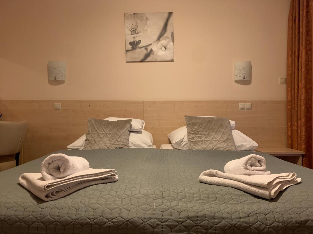 1 dormitorio con 2 camas y toallas en una cama en Nimród Hotel és Ètterem en Mosonmagyaróvár