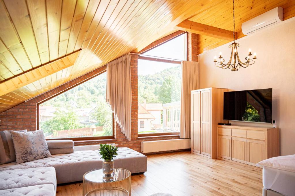 a living room with a couch and a large window at Rezort Sivý Kameň in Podhradie