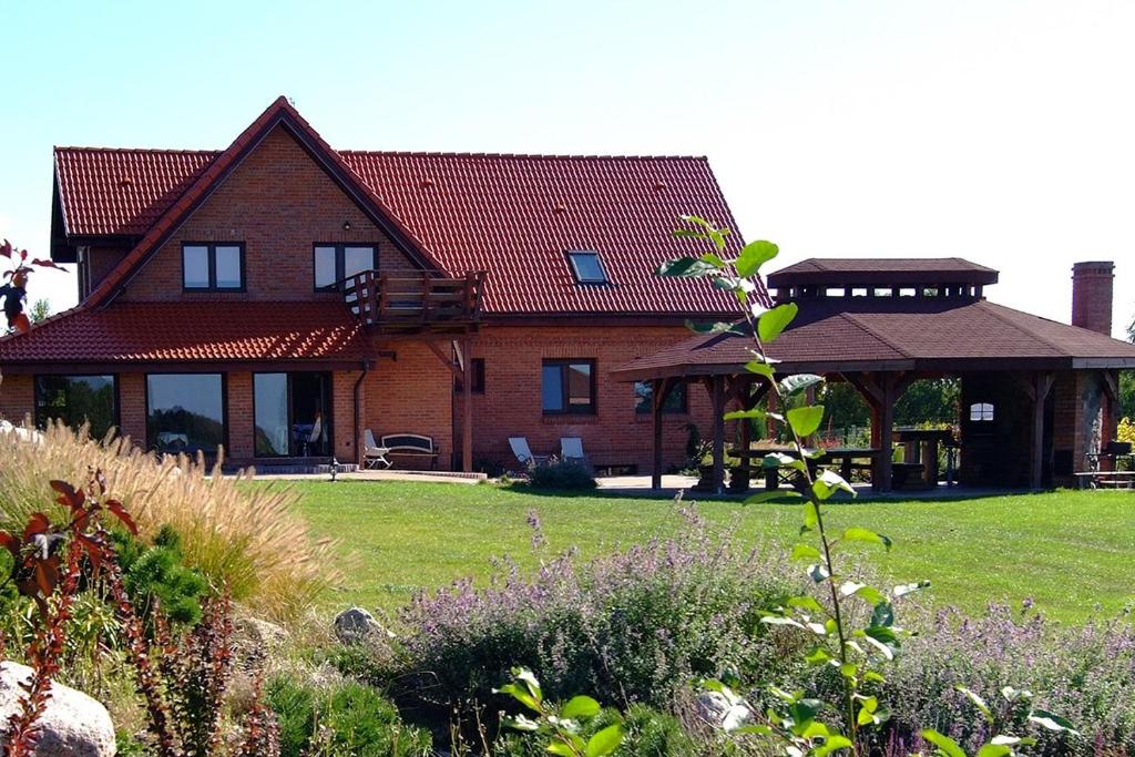 a large brick house with a gazebo at Mazury całoroczny dom nad jeziorem do wynajęcia z własną linią brzegową in Pasym
