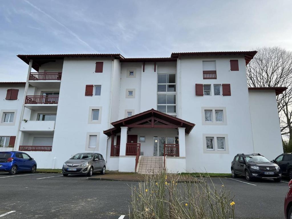 a large white building with cars parked in a parking lot at Appartement Cambo-les-Bains, 2 pièces, 2 personnes - FR-1-495-74 in Cambo-les-Bains