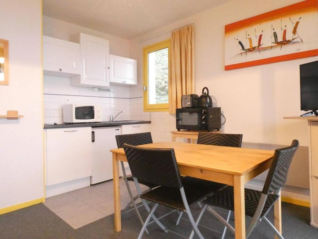 une cuisine et une salle à manger avec une table et des chaises en bois dans l'établissement Studio cosy pour 4 avec terrasse à Saint-Lary-Soulan - FR-1-457-277, à Saint-Lary-Soulan