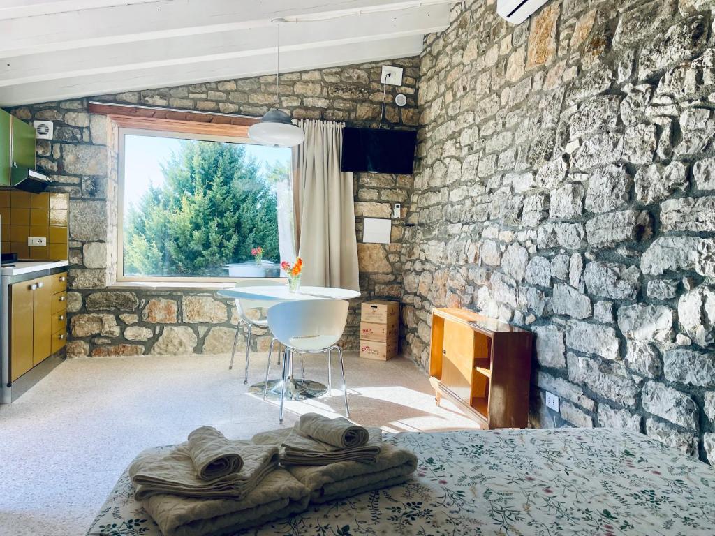 una camera da letto con un muro in pietra, un tavolo e un letto di LA CASETTA SULLE NUVOLE PETRA a Cammarata