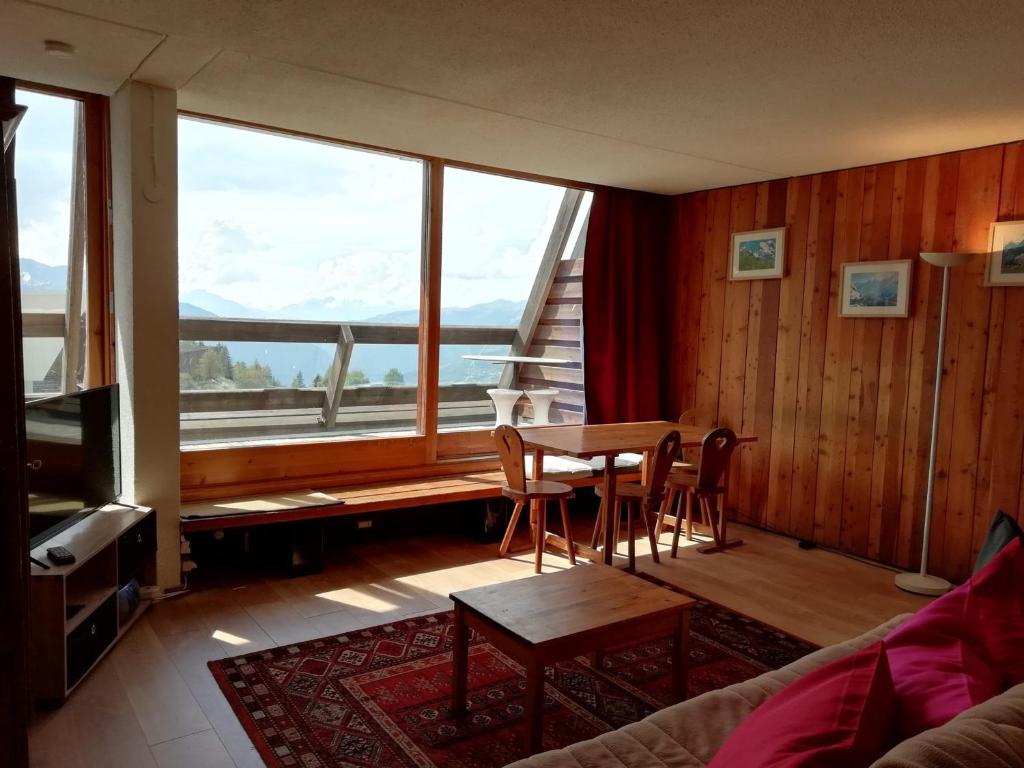 Una sala de estar con una mesa y sillas y una gran ventana. en Appartement 2 pièces cabine, 7 pers, Arc 1600, ski aux pieds, proche commerces, balcon sud - FR-1-411-669, en Arc 1600