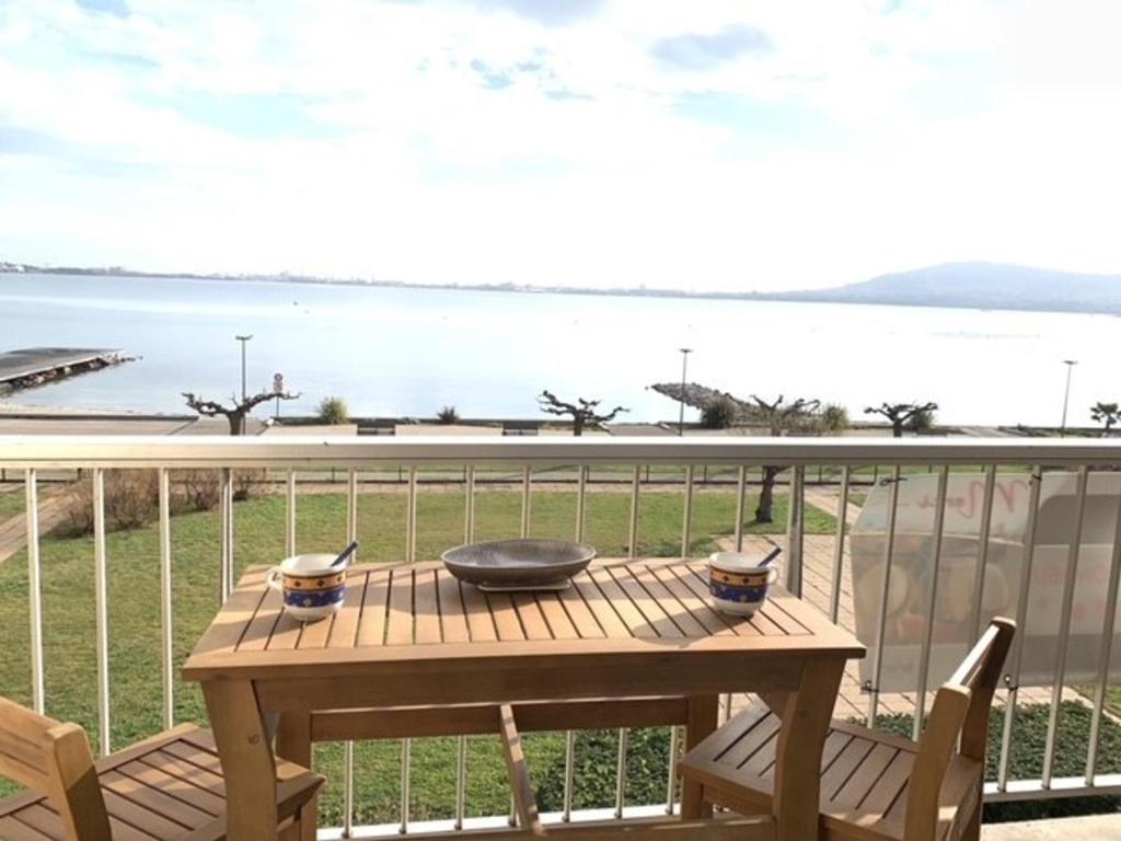 - une table en bois sur un balcon avec vue sur l'eau dans l'établissement Studio Balaruc-les-Bains, 1 pièce, 4 personnes - FR-1-503-7, à Balaruc-les-Bains