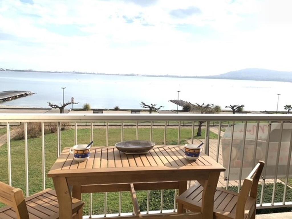 - une table en bois sur un balcon avec vue sur l'eau dans l'établissement Appartement cosy face à l'étang de Thau, proche thermes et commerces, balcon, animaux admis - FR-1-503-7, à Balaruc-les-Bains