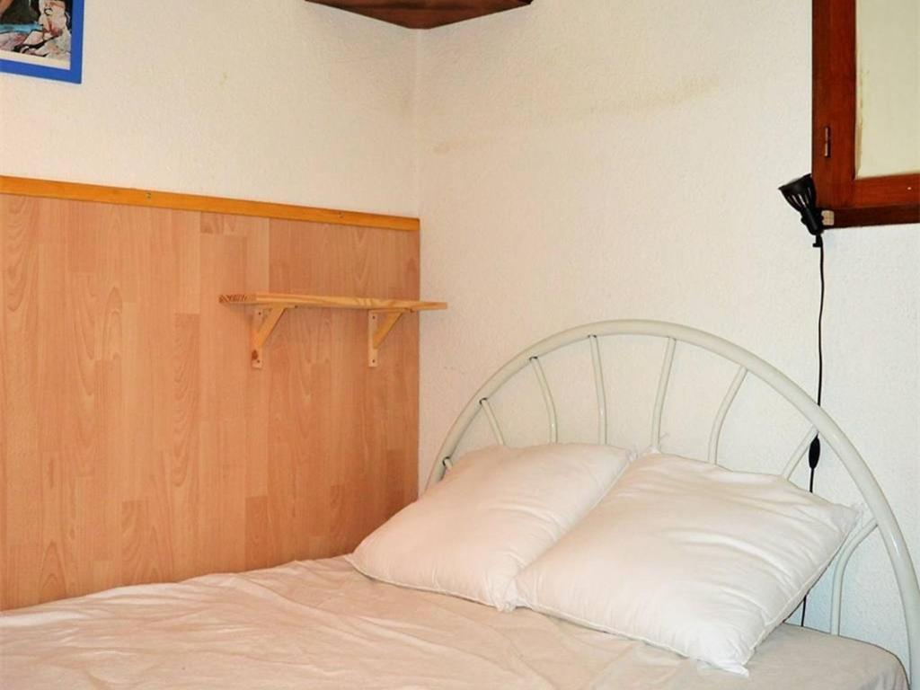 a bed in a room with a white pillow at Appartement calme centre station avec parking - FR-1-593-41 in Les Angles