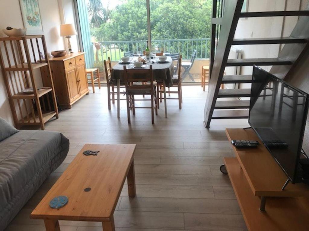 a living room with a table and a spiral staircase at Appartement Argelès-sur-Mer, 3 pièces, 6 personnes - FR-1-388-167 in Argelès-sur-Mer