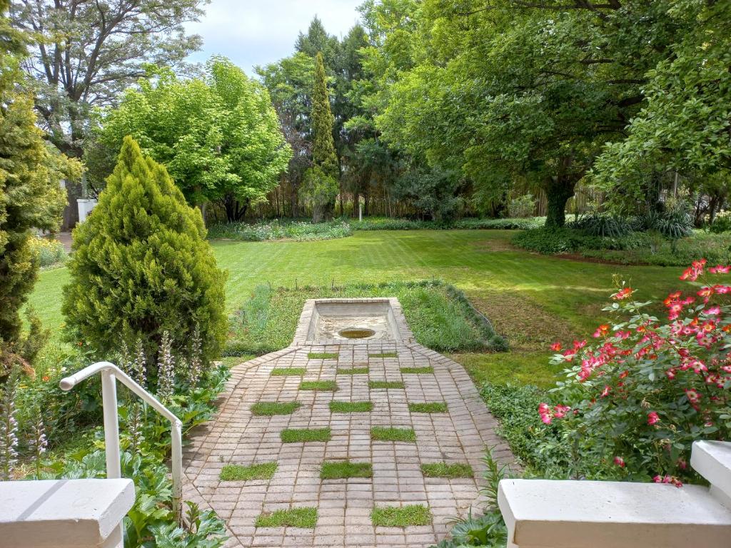 a garden with a brick pathway with flowers and trees at Karooland Gastehuis in Middelburg