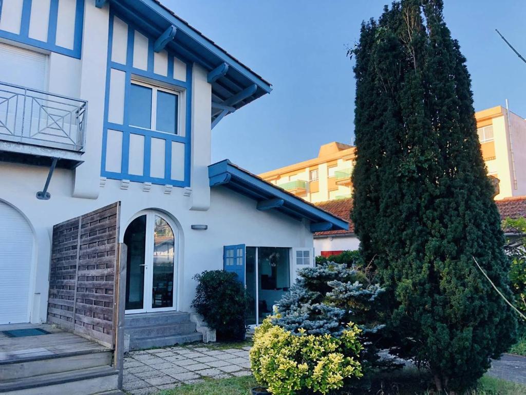 une maison blanche avec un grand arbre devant elle dans l'établissement Maison conviviale à Arcachon-le-Moulleau, à 150m de la plage, jardin, parking, 2 chambres - FR-1-433-64, à Arcachon