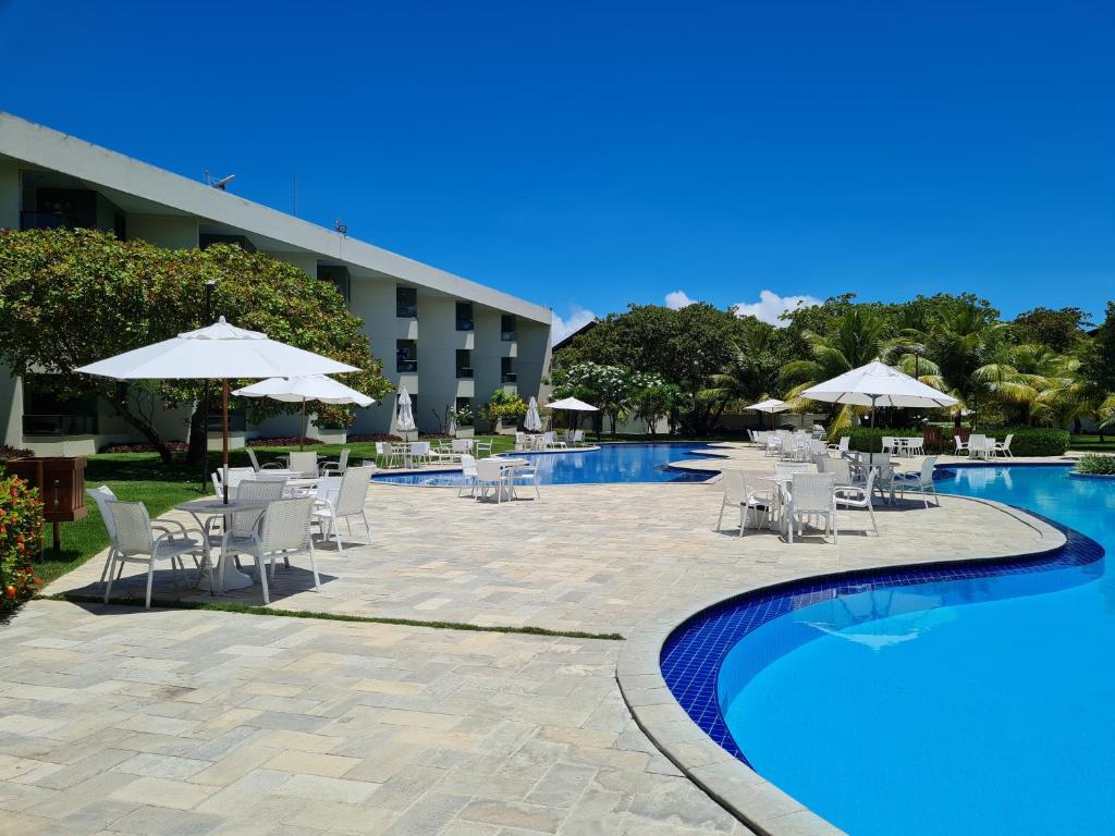 una piscina con sillas y sombrillas junto a un hotel en Flat Praia Dos Carneiros en Tamandaré