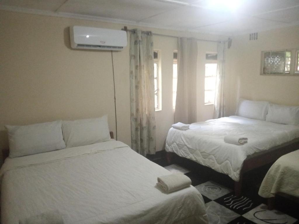 Habitación con 2 camas y ventana en Blue Waxbill Lodge, en Namzunga