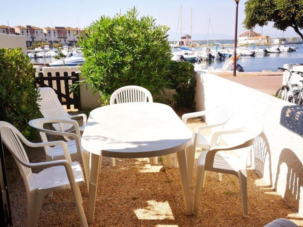 une table et des chaises blanches sur un balcon avec un port de plaisance dans l'établissement T2 4 pers Le Barcarès RDC Piscine Parking Animaux - FR-1-195-68, au Barcarès
