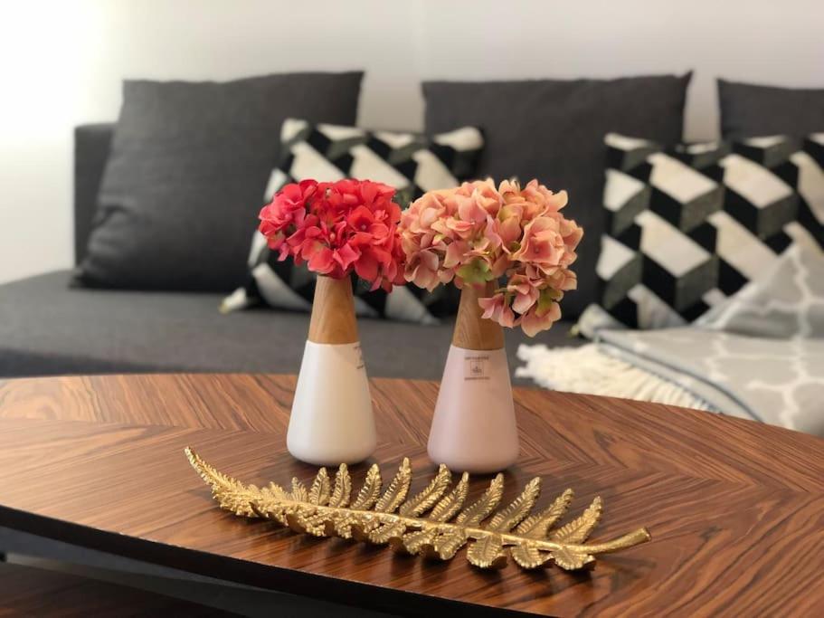 Tre vasi bianchi con fiori su un tavolino. di Central Apartment in the heart of the Marais a Parigi