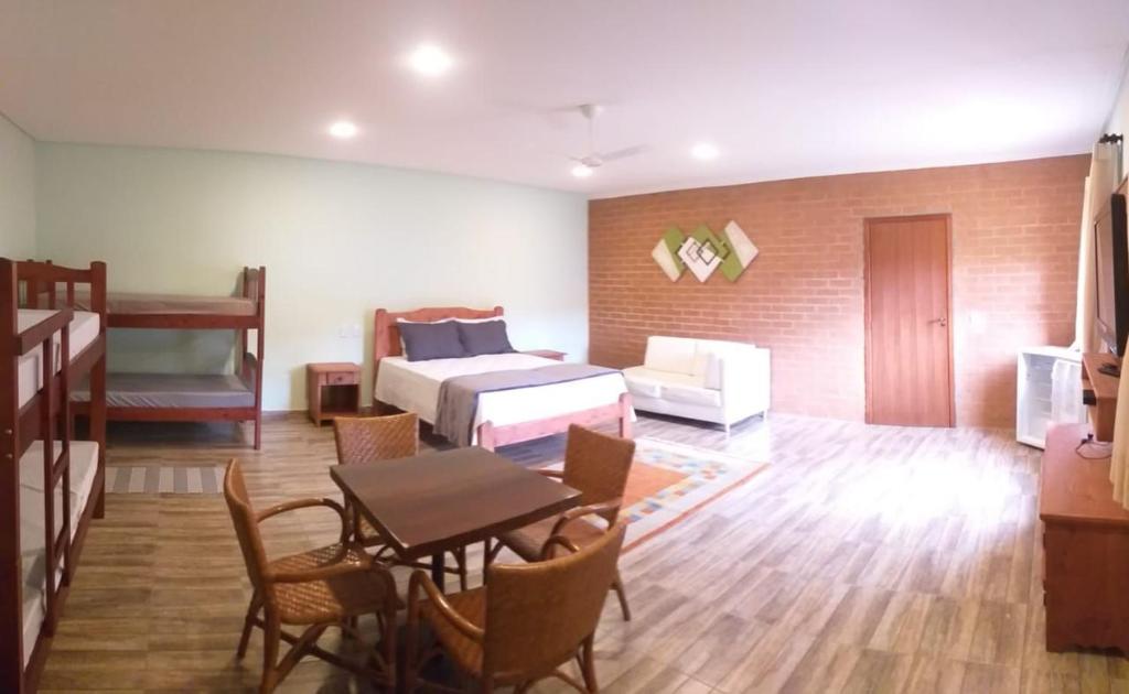 um quarto com uma cama, uma mesa e cadeiras em Chacara bora bora em São Bento do Sapucaí