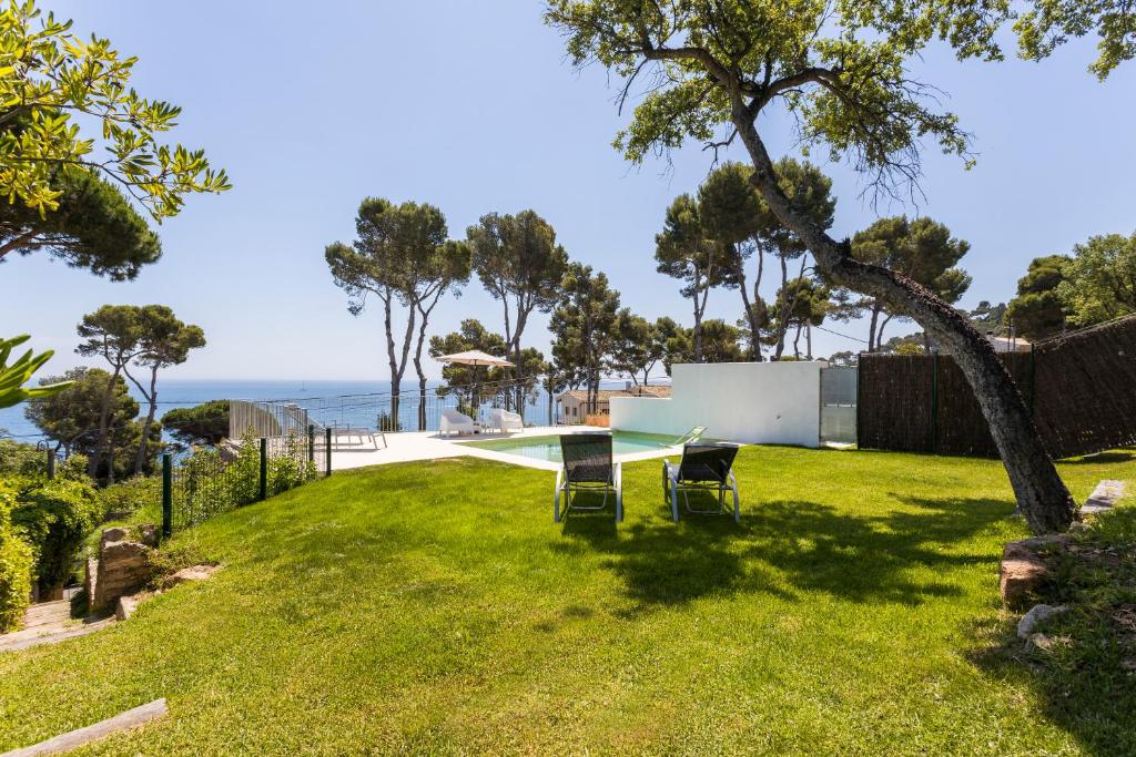 卡萊利亞德帕拉弗魯赫爾的住宿－Luxury Villa in front of the beach POPETA，一个带桌椅的后院和大海