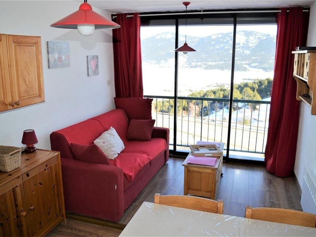 uma sala de estar com um sofá vermelho e uma grande janela em Studio Les Angles, 1 pièce, 4 personnes - FR-1-593-8 em Les Angles