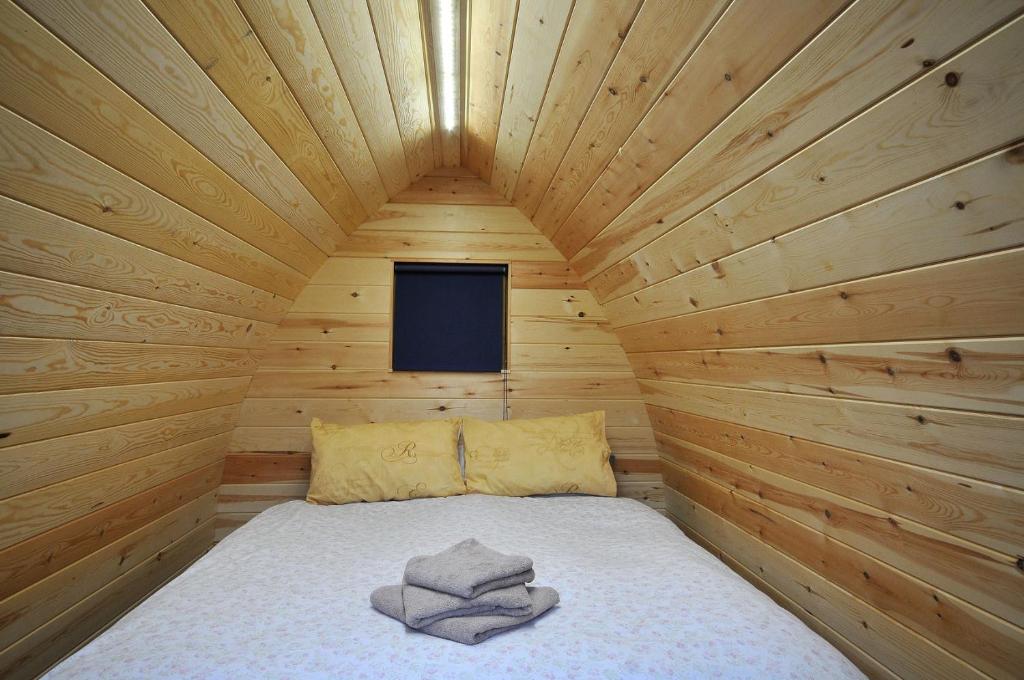 a bed in a wooden cabin with towels on it at Wolds Glamping in Pocklington