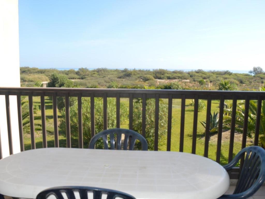 une table blanche et des chaises sur un balcon dans l'établissement Appartement front de mer avec piscine, 6 couchages, animaux admis - FR-1-225D-83, à Saint Cyprien Plage
