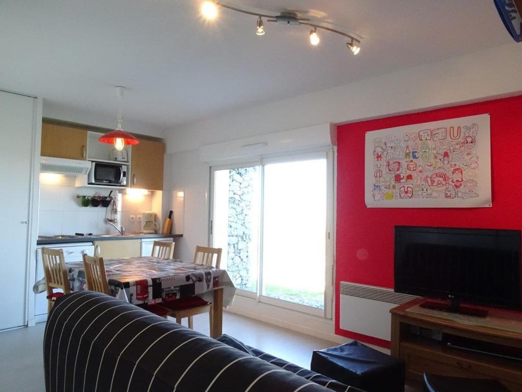 - un salon avec une table et un mur rouge dans l'établissement Appartement cosy 6 pers, accès direct pistes, Arette – TV, cuisine équipée, parking gratuit - FR-1-602-37, à Arette