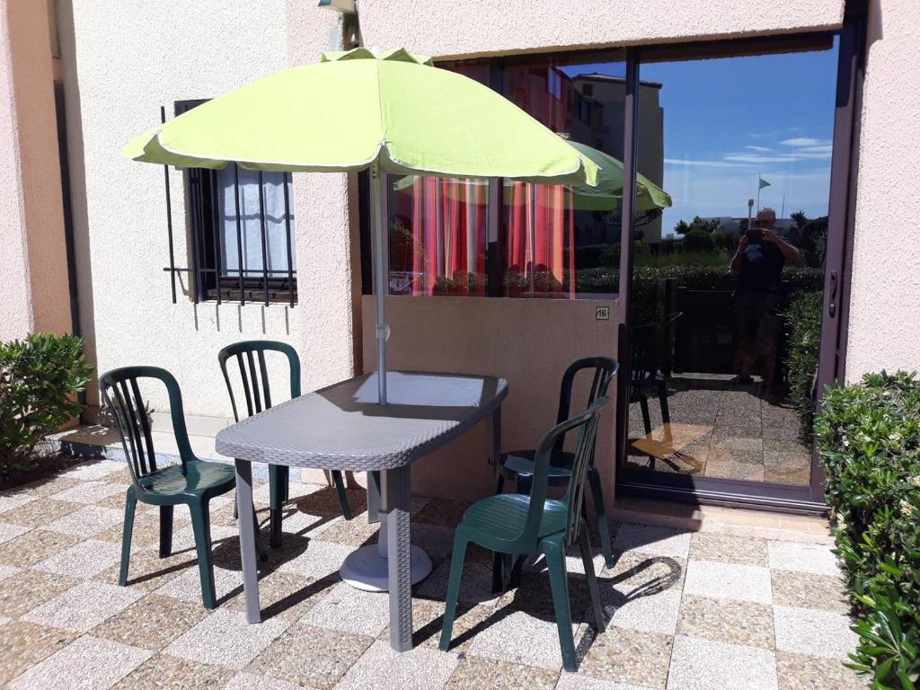 une table et des chaises avec un parasol sur une terrasse dans l'établissement T2 Cabine 4 pers, Terrasse, Parking, Plage à 50m - FR-1-81-529, au Barcarès