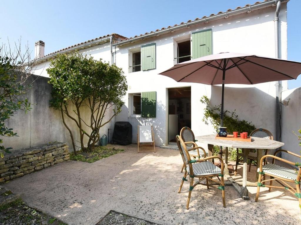 - une table et des chaises avec un parasol en face d'une maison dans l'établissement Maison Saint-Clément-des-Baleines, 3 pièces, 4 personnes - FR-1-434-74, à Saint-Clément-des-Baleines