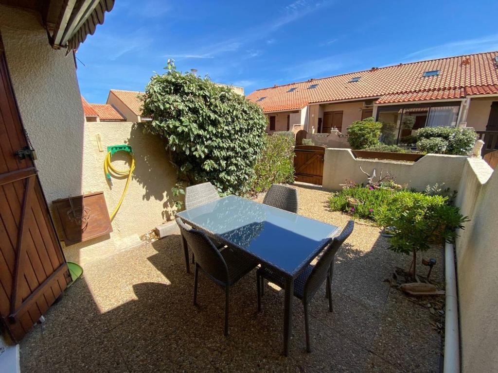 un patio avec une table et des chaises dans une cour dans l'établissement Villa climatisée 4 pers, proche plage, terrasse, Aqualand à 2,5 km - FR-1-81-533, à Leucate