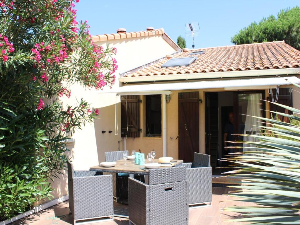 un patio avec une table et des chaises devant une maison dans l'établissement Maison avec terrasse, piscine, clim et parking - Gruissan - FR-1-229-779, à Gruissan