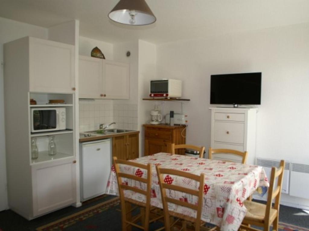 une cuisine avec une table et des chaises ainsi qu'une télévision dans l'établissement Studio cabine 4 pers pied des pistes, Les Adrets-Prapoutel - FR-1-557-39, à Les Adrets