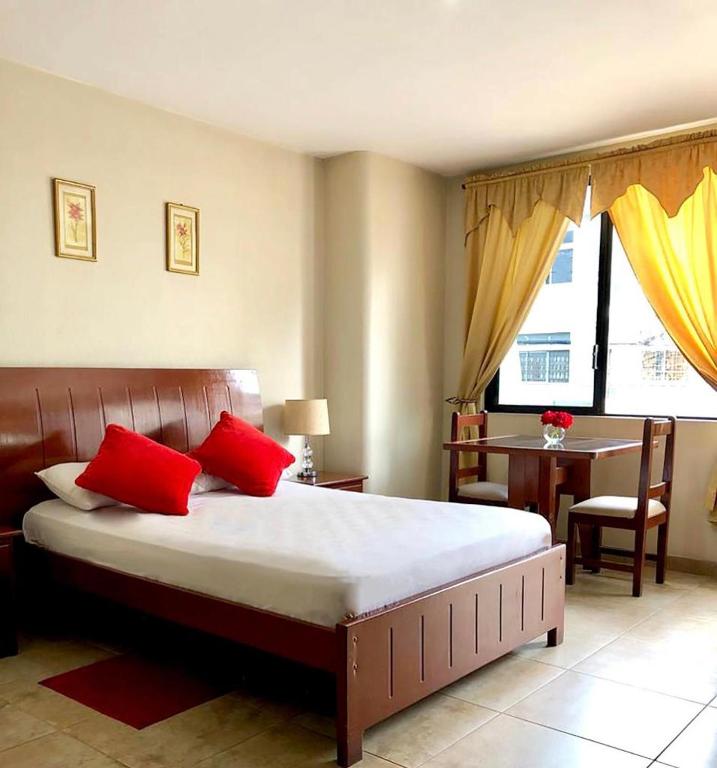 una camera da letto con un letto con cuscini rossi e un tavolo di Hotel Onix Gold a Guayaquil