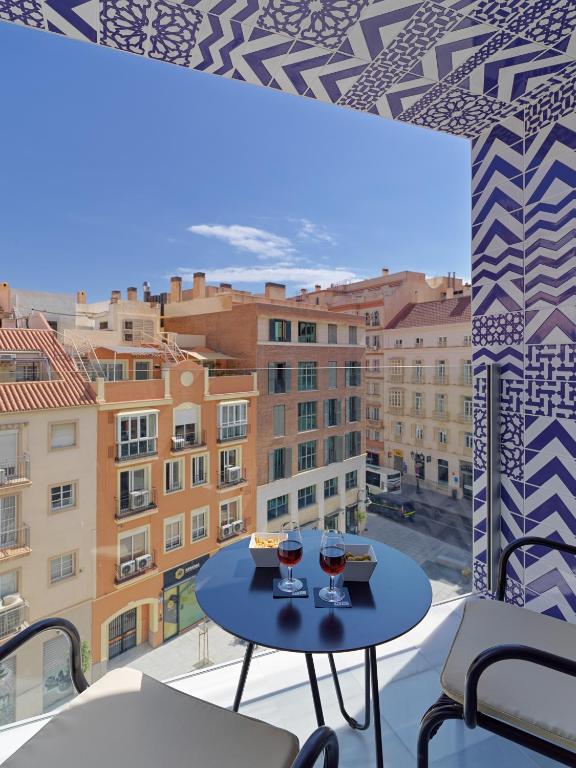 stół z dwoma kieliszkami wina na balkonie w obiekcie H10 Croma Málaga w Maladze