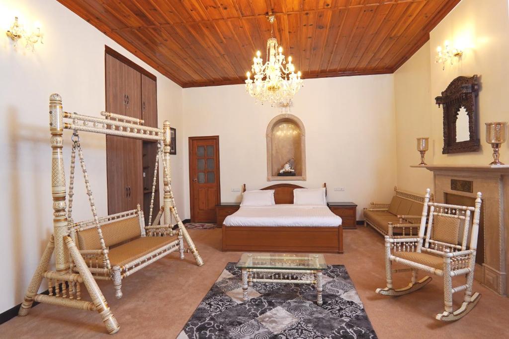 a bedroom with a bed and two chairs and a fireplace at The Edgeworth in Shimla