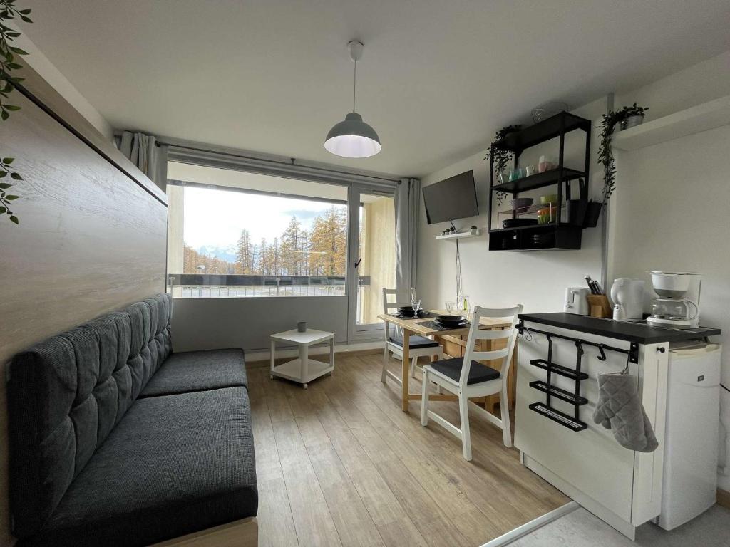un salon avec un canapé et une cuisine avec une table dans l'établissement Studio rénové au pied des pistes, balcon ouest, 4 couchages à Montgenèvre - FR-1-330D-129, à Montgenèvre