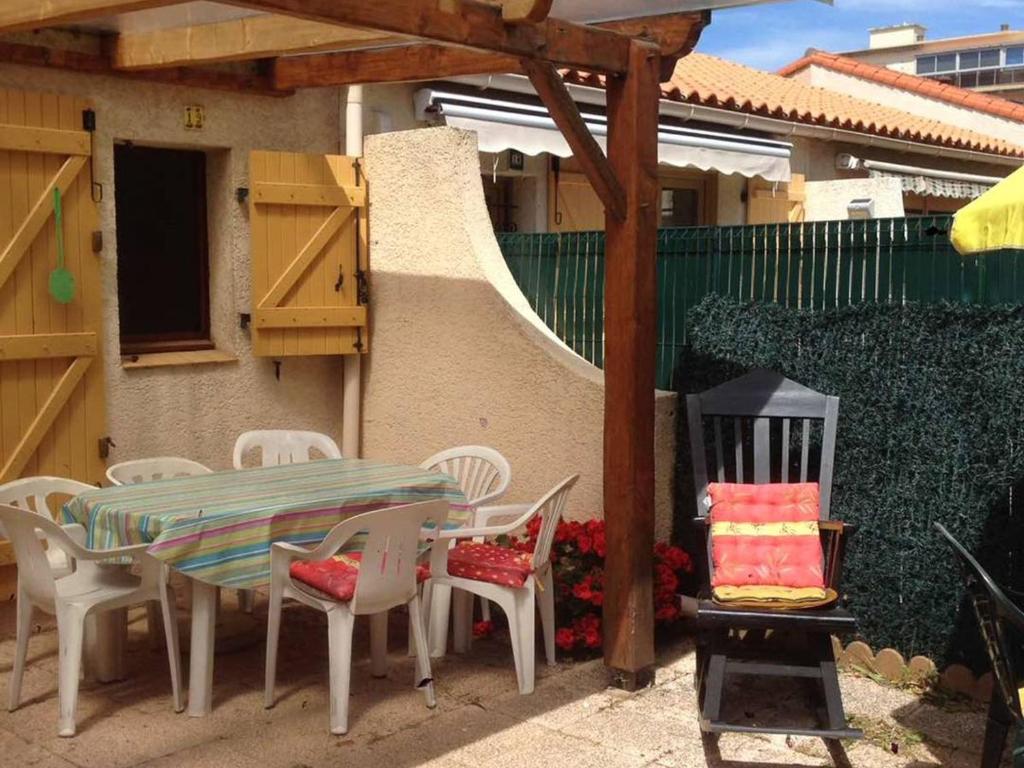 un patio avec une table et des chaises devant une maison dans l'établissement Charmant Pavillon pour 6, Piscine et Parking Privé, à 300m de la Plage - Argelès-sur-Mer - FR-1-388-191, à Argelès-sur-Mer