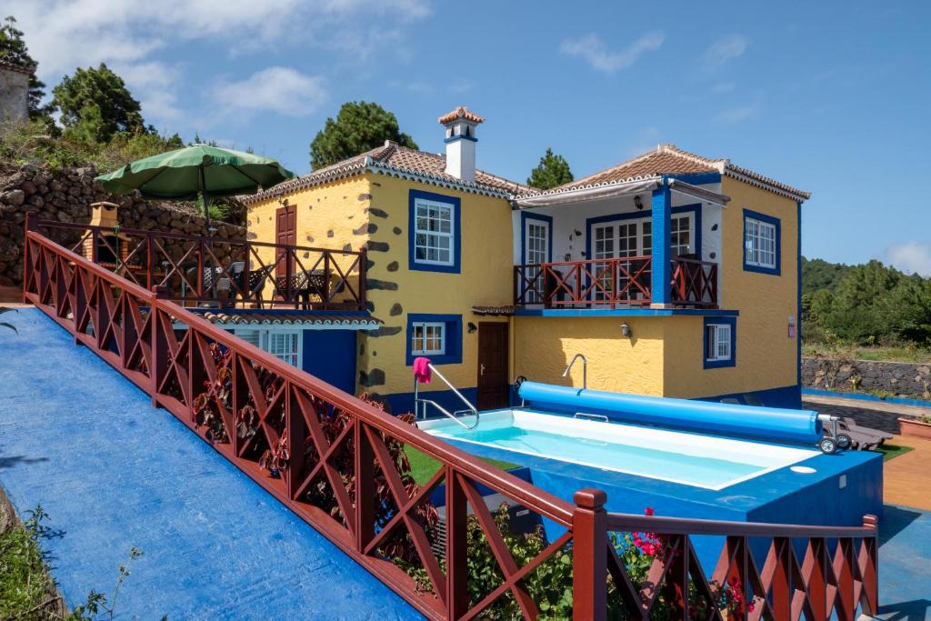 una casa con un puente sobre una piscina en CASA ALBA, casa rústica en la colina con piscina-spa climatizada y vistas al mar, en Puntallana