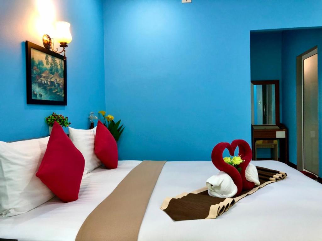 a bedroom with a bed with red and white pillows at Pana Long Beach Resort - SHA Plus in Ko Lanta