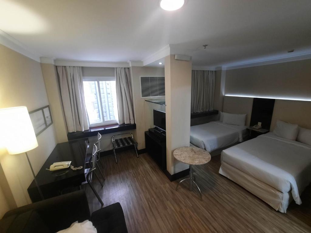 een hotelkamer met 2 bedden en een bureau bij Flat confortável ao lado da Paulista in Sao Paulo