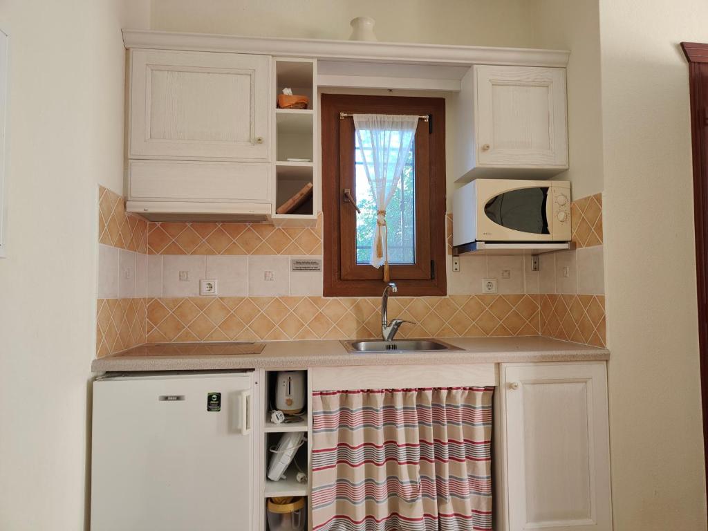 a kitchen with white cabinets and a sink and a microwave at Alkyon Villas in Syvota