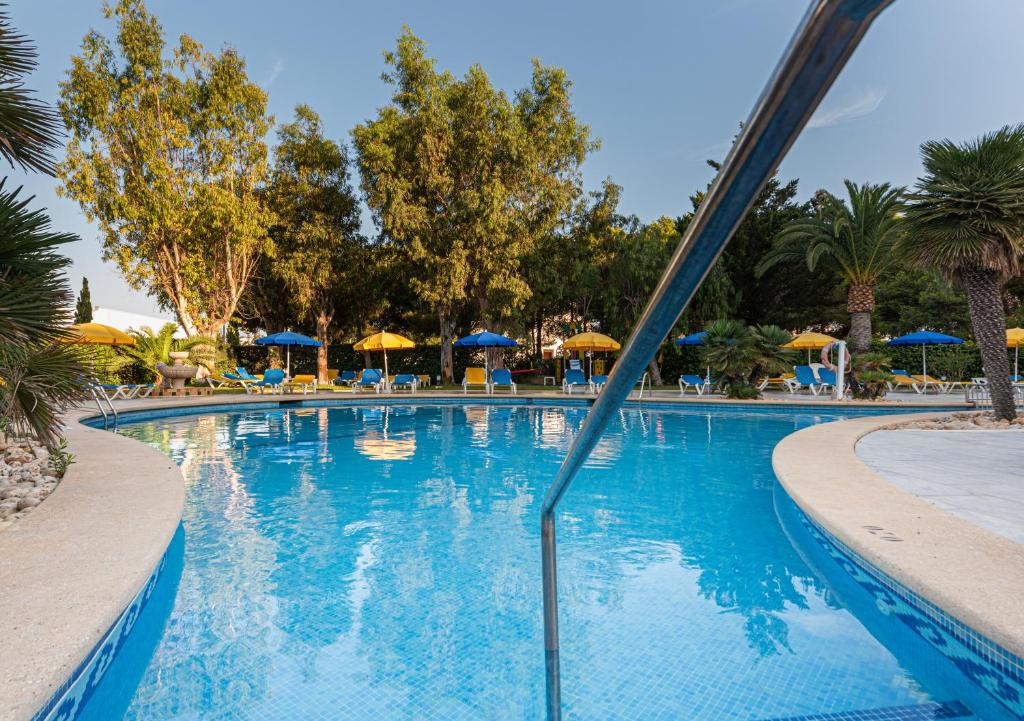 a large swimming pool with chairs and umbrellas at Hotel La Santa Maria in Cala Millor
