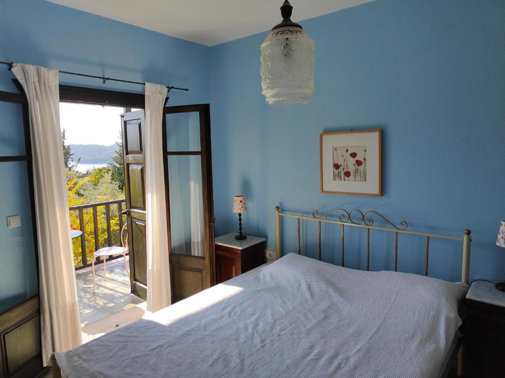 a blue bedroom with a bed and a balcony at Alkyon Villas in Syvota