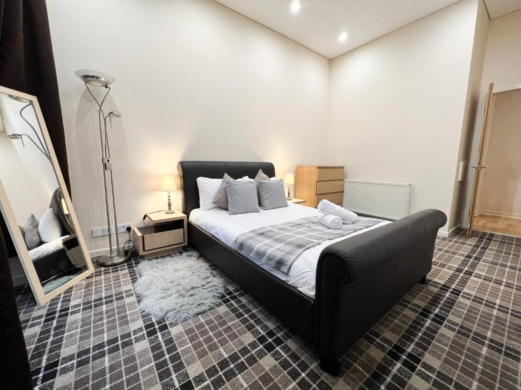 a bedroom with a large bed with a black couch at Queen Street City Centre Apartment in Glasgow