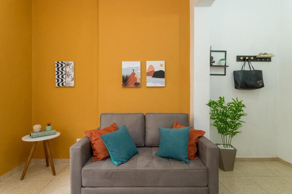 sala de estar con sofá gris y almohadas de color naranja y azul en Conforto e relax, caminhando para a Praia de Copacabana, Quarto e Sala, completo, com wi fi, cozinha, ar condicionado, en Río de Janeiro