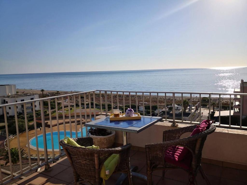 un balcon avec une table et des chaises et l'océan dans l'établissement Grand T4 au Barcarès avec Vue Mer et Parking - 3 Chambres, Terrasse, Proche plage - FR-1-81-525, au Barcarès