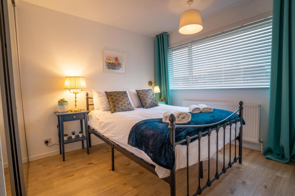 a bedroom with a bed and a window with green curtains at Saltbox Stays- 3 bed house with off-street parking, sleeps 6 in Newhall