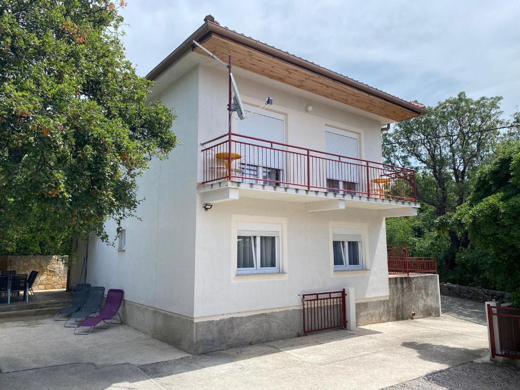 een wit huis met een balkon en paarse stoelen bij Holiday home Povile in Novi Vinodolski