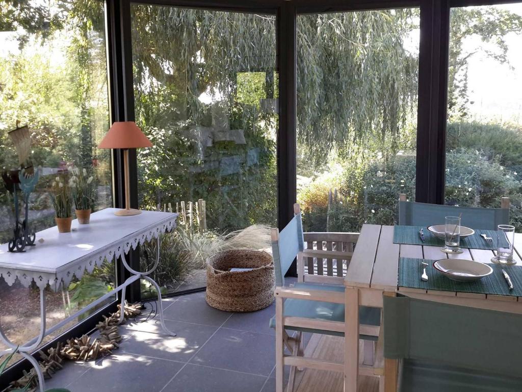 un patio con mesa, sillas y una ventana grande en Maison Pleumeur-Bodou, 4 pièces, 6 personnes - FR-1-542-28, en Pleumeur-Bodou