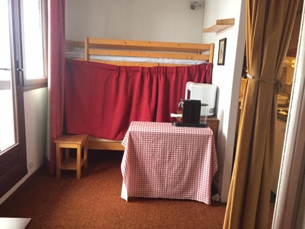 a room with a table and a bed with a red curtain at Studio coin montagne à Risoul 1850 - FR-1-330-541 in Risoul
